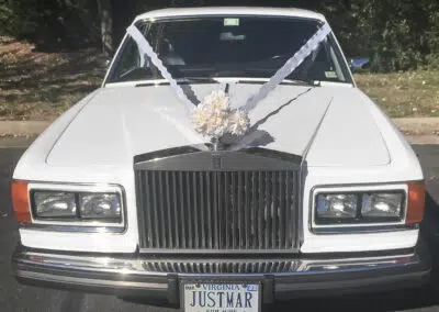 Photo of white Rolls Royce displaying typical English style hood decorations